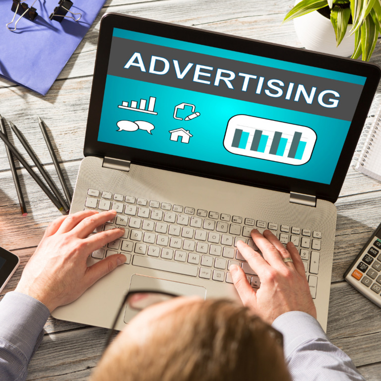 Digital marketing professional analyzing an advertising campaign dashboard on a laptop with data visualization charts.